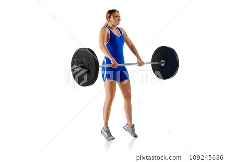 Young athletic girl, weightlifter training, lifting heavy weight, barbell against white background Young athletic girl, weightlifter training, lifting heavy weight, barbell against white background 109245686