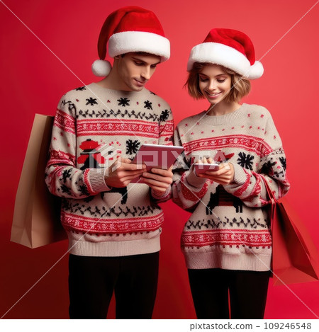 funny sweet young loving couple dressed print pullover buying christmas gifts typing modern gadget on red color background funny sweet young loving couple dressed print pullover buying christmas gifts typing modern gadget on red color background 109246548