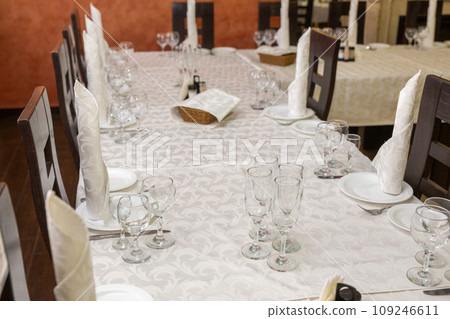 Served festive table with dishes, glasses, glasses, cutlery and napkins for a banquet Served festive table with dishes, glasses, glasses, cutlery and napkins for a banquet 109246611