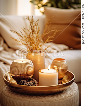 Cozy winter home decor arrangement with burning candles, holiday room interior decorations in white and gold tones 109248497