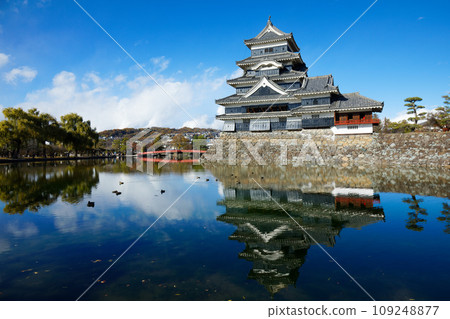Matsumoto Castle in autumn leaves and the scenery reflected on the water surface, the mountain range of the Northern Alps Matsumoto Castle in autumn leaves and the scenery reflected on the water surface, the mountain range of the Northern Alps 109248877