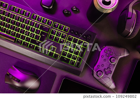 Green lit keyboard amidst various wireless devices 109249802