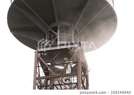 Sand blasting process. Industrial worker in protective uniform cleaning surface of big steel construction before painting on high altitude. Sand blasting process. Industrial worker in protective uniform cleaning surface of big steel construction before painting on high altitude. 109249840