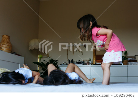three children playing jumping on parents bed 109250402