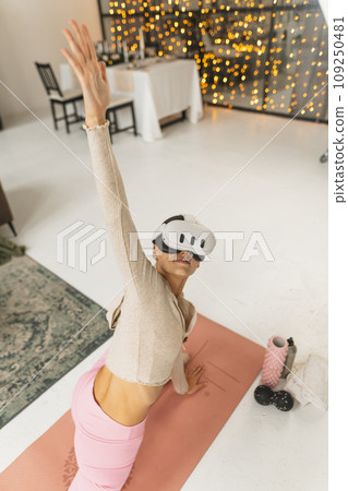 Performing arm stretches while participating in home workouts using a virtual reality headset during the Christmas period. Performing arm stretches while participating in home workouts using a virtual reality headset during the Christmas period. 109250481