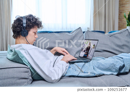 Online meeting with psychologist, young man lying on couch using video conference on laptop Online meeting with psychologist, young man lying on couch using video conference on laptop 109251677