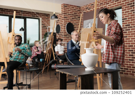 Group of diverse people learn how to draw realistic items, listening teacher and drawing on canvas. Family involved in art activity spending time together. Creative leisure activities for adults 109252401