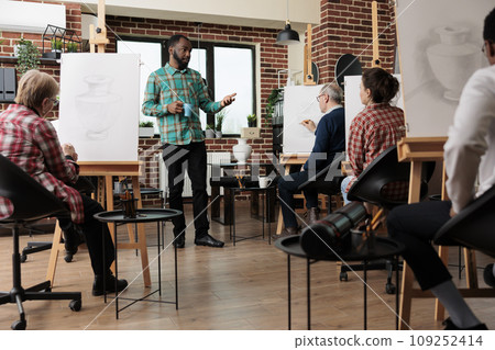 Group of people learn to draw at art studio, enjoying drawing group class, working together in classroom. Creative activities for adults to develop new artistic skills and relieve stress 109252414