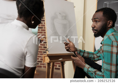 Meeting new friends in art class. Two young African American students man and woman talking communicating during drawing lesson, young black couple learning new things together 109252516