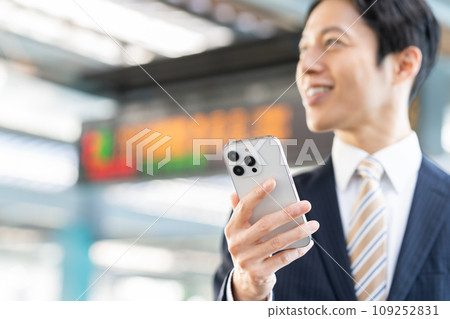A middle-aged businessman looking at his smartphone at the station. Photographed in cooperation with Keio Electric Railway Co., Ltd. 109252831