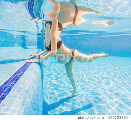 Embracing aquatic fitness, a pregnant woman demonstrates strength and serenity in underwater aerobics, creating a serene and empowering image in the pool Embracing aquatic fitness, a pregnant woman demonstrates strength and serenity in underwater aerobics, creating a serene and empowering image in the pool 109253864