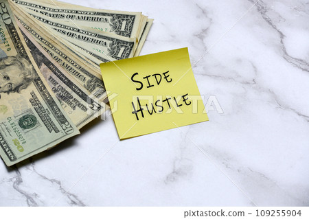 Dollars bill and stick note with text written SIDE HUSTLE on mable table. Dollars bill and stick note with text written SIDE HUSTLE on mable table. 109255904