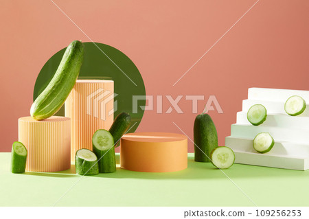 A set of cylinder podiums arranged with a white staircase and cucumber cut in halves and slices. Pedestal or platform for beauty products presentation A set of cylinder podiums arranged with a white staircase and cucumber cut in halves and slices. Pedestal or platform for beauty products presentation 109256253
