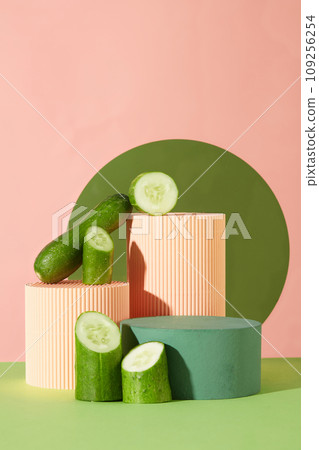Three podiums in coral and green color decorated with halves of cucumber. Concept scene stage showcase for new product, promotion sale, cosmetic presentation Three podiums in coral and green color decorated with halves of cucumber. Concept scene stage showcase for new product, promotion sale, cosmetic presentation 109256254