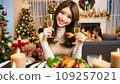 A cute Japanese woman is drinking champagne while eating chicken at a Christmas party 109257021