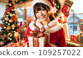 A cute Japanese woman is wearing a Santa costume and holding a present. 109257022