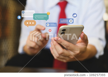 Businessman using mobile phone with icons social media notifications, messages and comments Businessman using mobile phone with icons social media notifications, messages and comments 109257393
