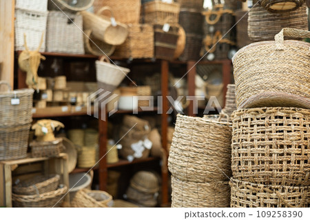Stack pile of wicker baskets, large and small, stand on top of each other in store 109258390