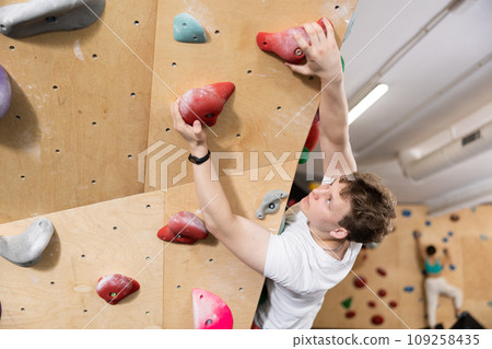 Male mountaineer climbing artificial rock wall without belay indoors 109258435