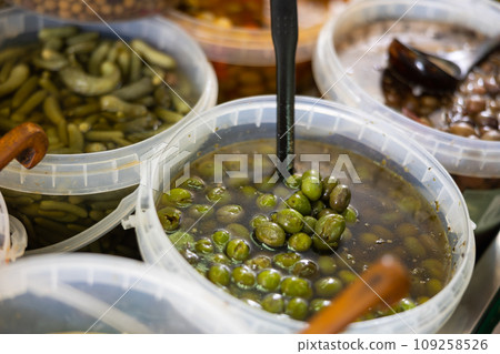Pickled green olives scooped with skimmer out of plastic bucket put on counter Pickled green olives scooped with skimmer out of plastic bucket put on counter 109258526