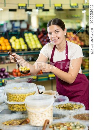 Young woman in uniform sells olives in supermarket 109258642