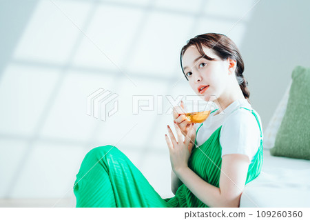 年輕女子在房間裡喝茶。 年輕女子在房間裡喝茶。 109260360