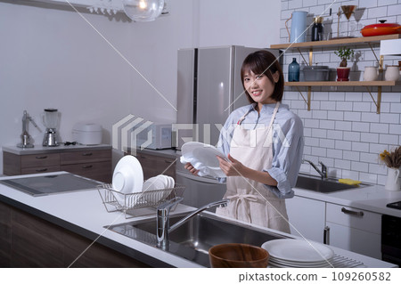 Woman wiping dishes in the kitchen Woman wiping dishes in the kitchen 109260582