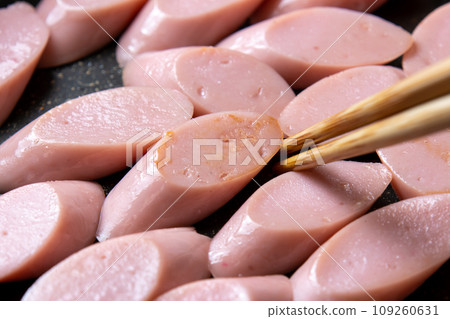 A cooking scene where fish sausage (diagonally cut) is stir-fried in a frying pan. A cooking scene where fish sausage (diagonally cut) is stir-fried in a frying pan. 109260631