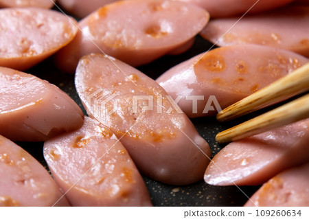 A cooking scene where fish sausage (diagonally cut) is stir-fried in a frying pan. 109260634
