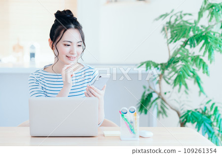 一位在客廳使用智能手機的年輕女子。 109261354