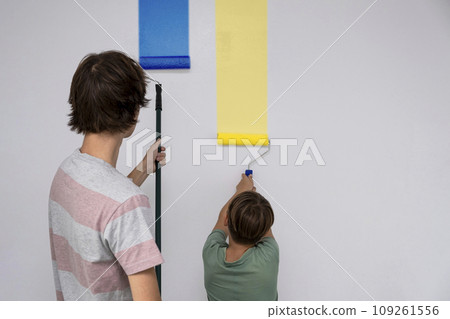 children paint the wall with a roller. teenagers spend time together helping to make repairs. children paint the wall with a roller. teenagers spend time together helping to make repairs. 109261556