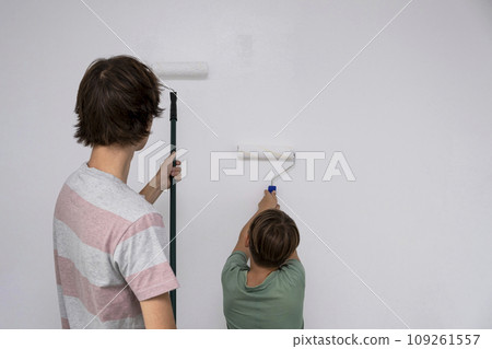 children paint the wall with a roller. teenagers spend time together helping to make repairs. children paint the wall with a roller. teenagers spend time together helping to make repairs. 109261557