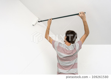 children paint the wall with a roller. teenagers spend time together helping to make repairs. 109261580