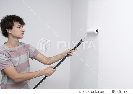 children paint the wall with a roller. teenagers spend time together helping to make repairs. 109261581