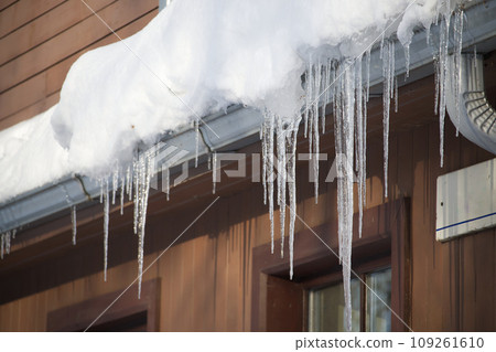 Large icicles hanging from the edge of a roof Large icicles hanging from the edge of a roof 109261610