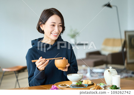 Woman eating breakfast in the living room Woman eating breakfast in the living room 109262742