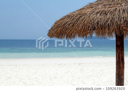 Tropical sea, shaded branches on a white sandy beach, parasols made from natural materials 109263920