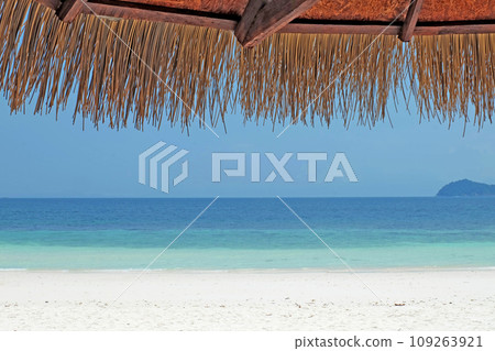 Tropical sea, shaded branches on a white sandy beach, parasols made from natural materials 109263921