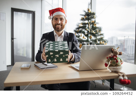 Man in Santa hat and suit showing festive cardboard box with online order Man in Santa hat and suit showing festive cardboard box with online order 109264452