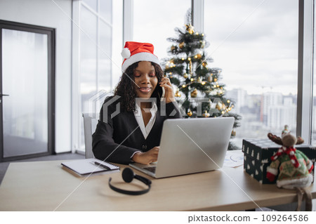 African woman talking on smartphone on background of Christmas tree. 109264586
