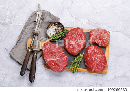 Raw beef fillet steaks on a cutting board, fresh and uncooked Raw beef fillet steaks on a cutting board, fresh and uncooked 109266283