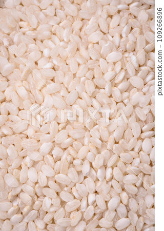 White uncooked rice in a round ceramic bowl on a dark concrete background 109266896