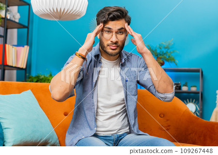 Sick ill Indian man rubbing temples to cure headache problem, suffering from migraine, stress 109267448