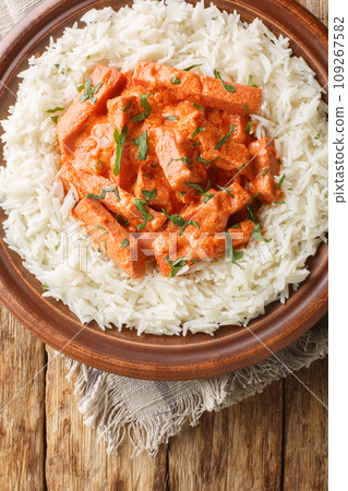 Classic Swedish dish Korvstroganoff of sausages with cream sauce and a side dish of rice close-up on a plate. Vertical top view 109267582