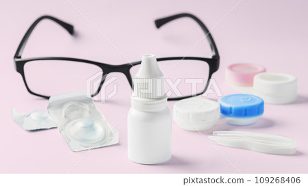 Eye drops bottle with contact lens, eyeglasses and accessories on pink background 109268406