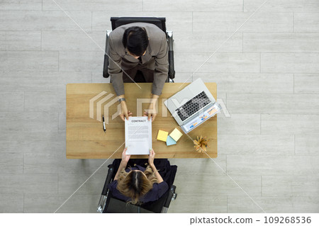Human Resource Manager in suit handing contract document to young candidate after the interview. Top View 109268536