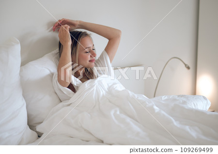 Young smiling girl waking up and stretching in bed 109269499
