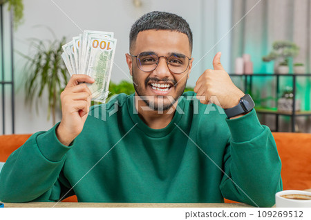 Smiling rich happy Indian man counting money cash calculate domestic bills at home apartment room Smiling rich happy Indian man counting money cash calculate domestic bills at home apartment room 109269512