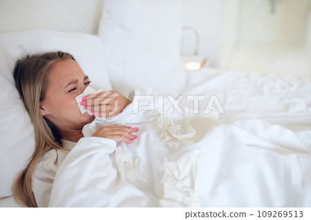 Girl lying in bed with runny nose and feeling bed Girl lying in bed with runny nose and feeling bed 109269513