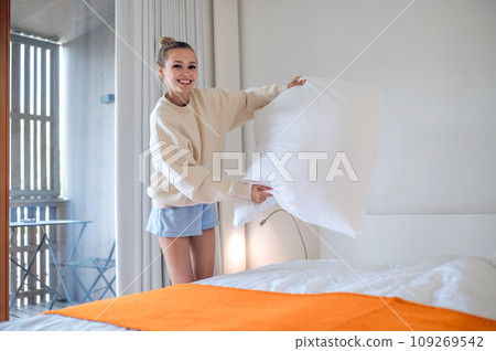 Girl in white making bed in the morning Girl in white making bed in the morning 109269542